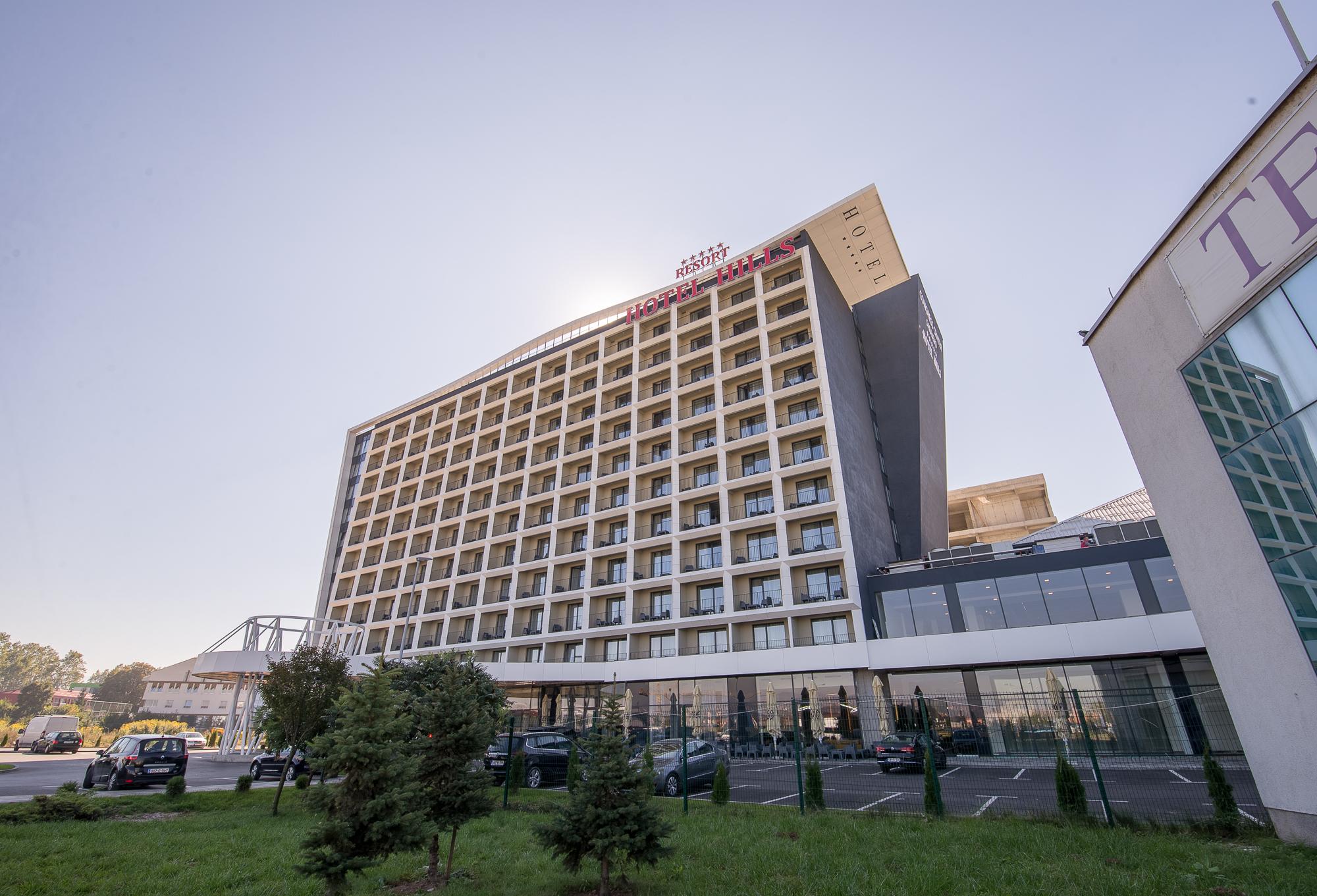 호텔 힐스 사라예보 콩그레스 앤 테르말 스파 리조트 Ilidža 외부 사진 The photo shows a modern hotel building with multiple floors and a contemporary design. The structure features large windows arranged in a grid pattern and a prominent entrance area at the bottom. There are green areas, possibly with trees or landsca